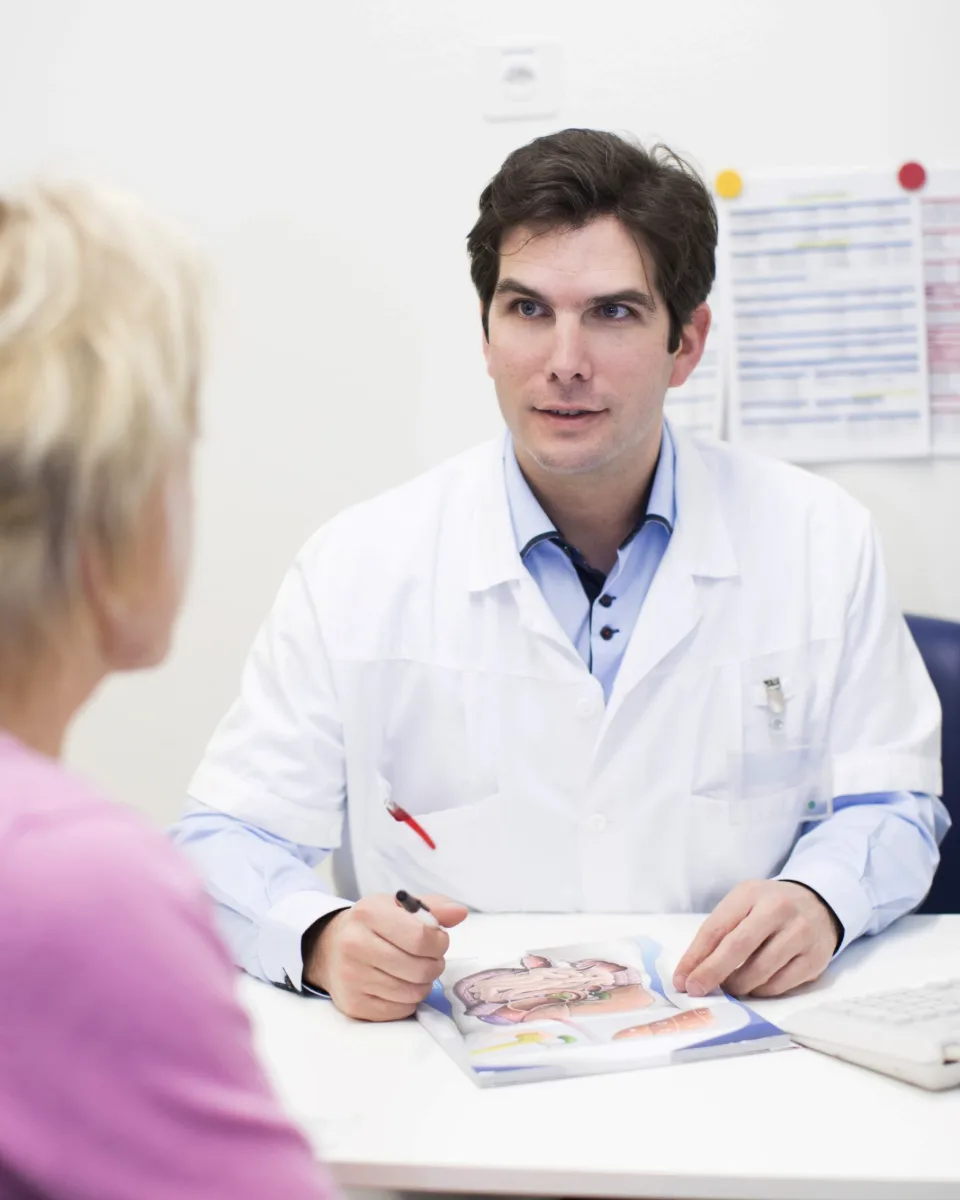 Le Dr Pierre Fournier en consultation, attentif, face à une personne vue de dos