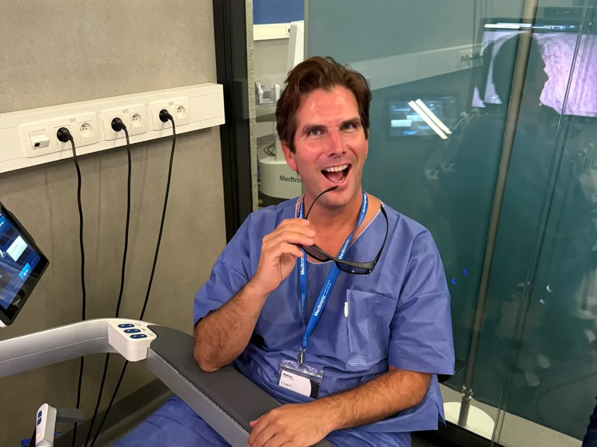 Le Dr Pierre Fournier, souriant, en tenue de bloc, assis à la console de chirurgie robot-assistée